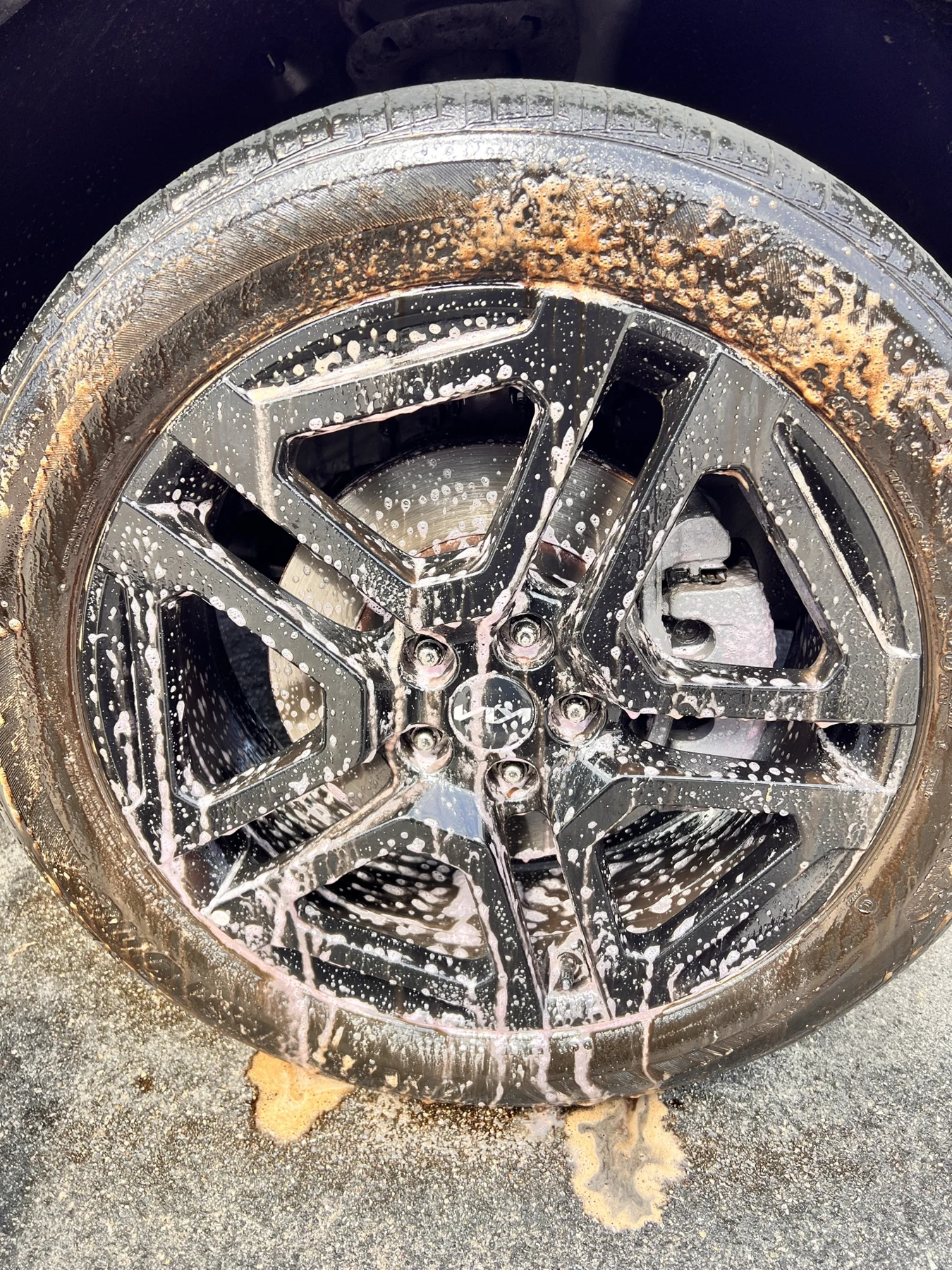 Wheel and tire being cleaned with foaming detailing solution